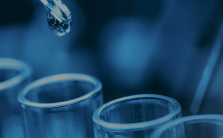 close-up of a dropper with a droplet hovering above test tubes