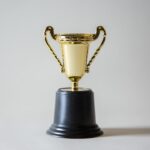 gold trophy on a black base with a plain background