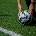 A person preparing to kick a colorful soccer ball on a green field