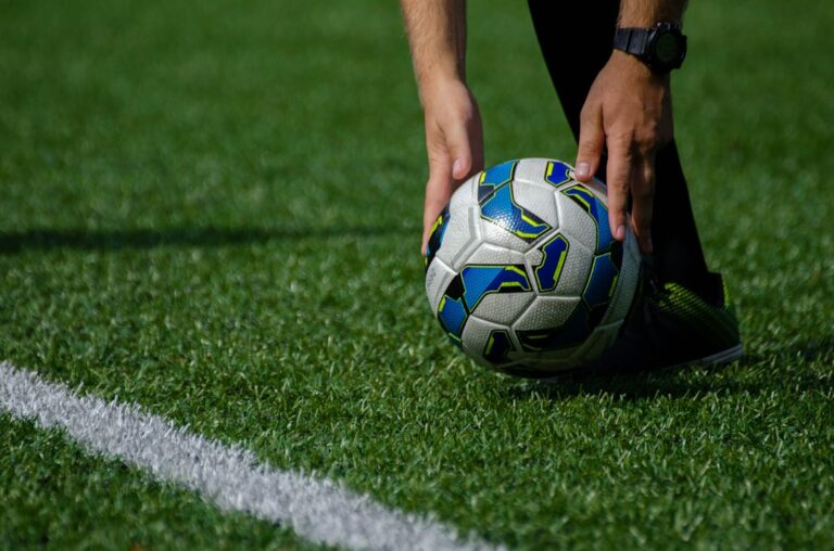 A person preparing to kick a colorful soccer ball on a green field